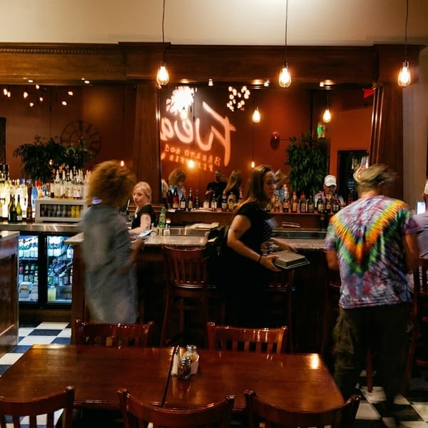 A lively bar scene with patrons, a well-stocked bar, and a television showing a game.